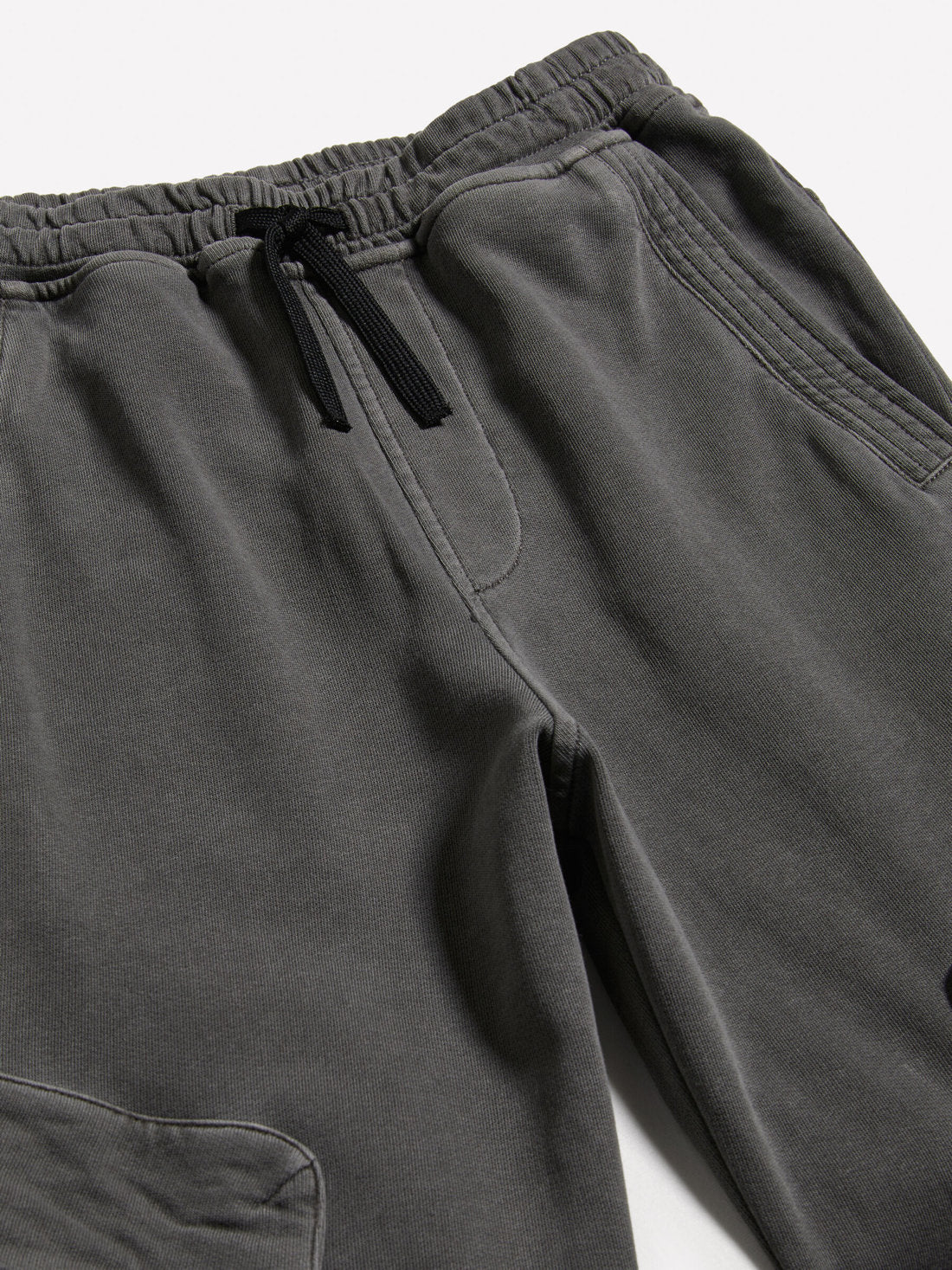 Close-up of the waistband and pocket detail of dark grey joggers, showing the drawstring and texture, a practical and stylish choice in Kuwait.