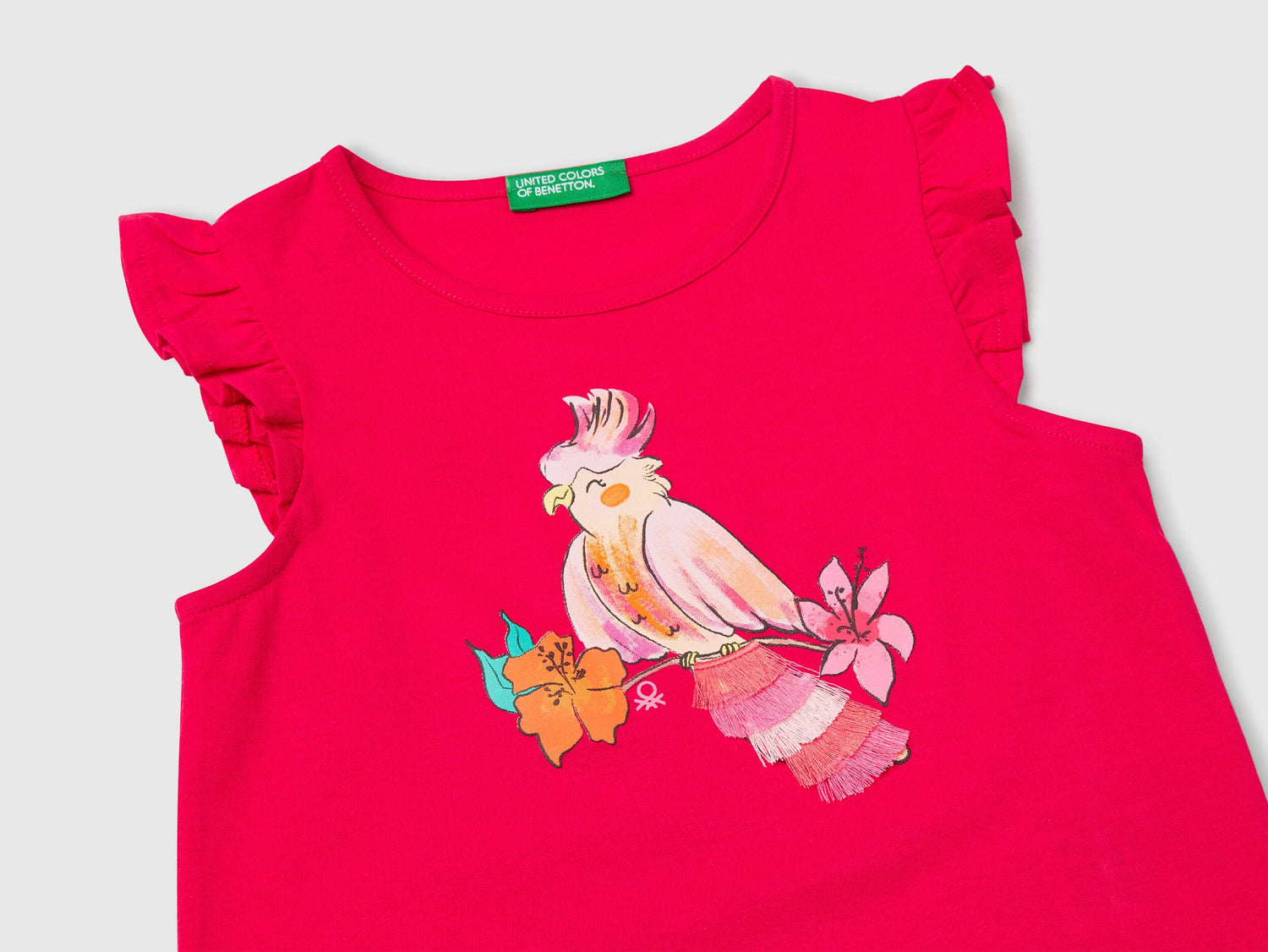 Close-up of the vibrant bird print on a fuchsia Benetton tank top, showing feather details.