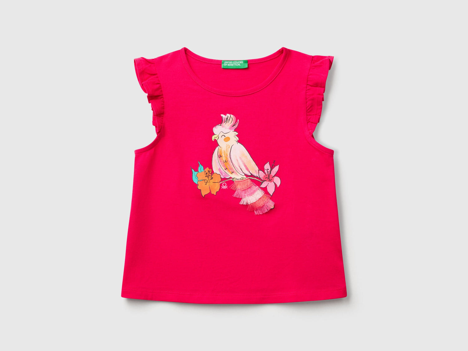 Front view of a fuchsia Benetton printed tank top with a colorful bird graphic and ruffle sleeves.