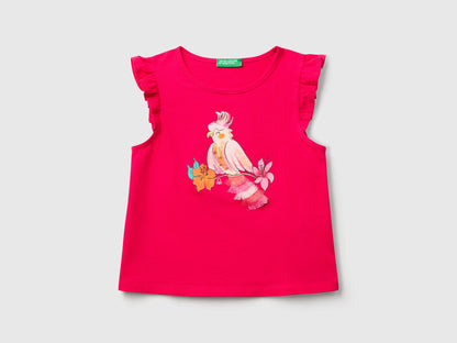 Front view of a fuchsia Benetton printed tank top with a colorful bird graphic and ruffle sleeves.