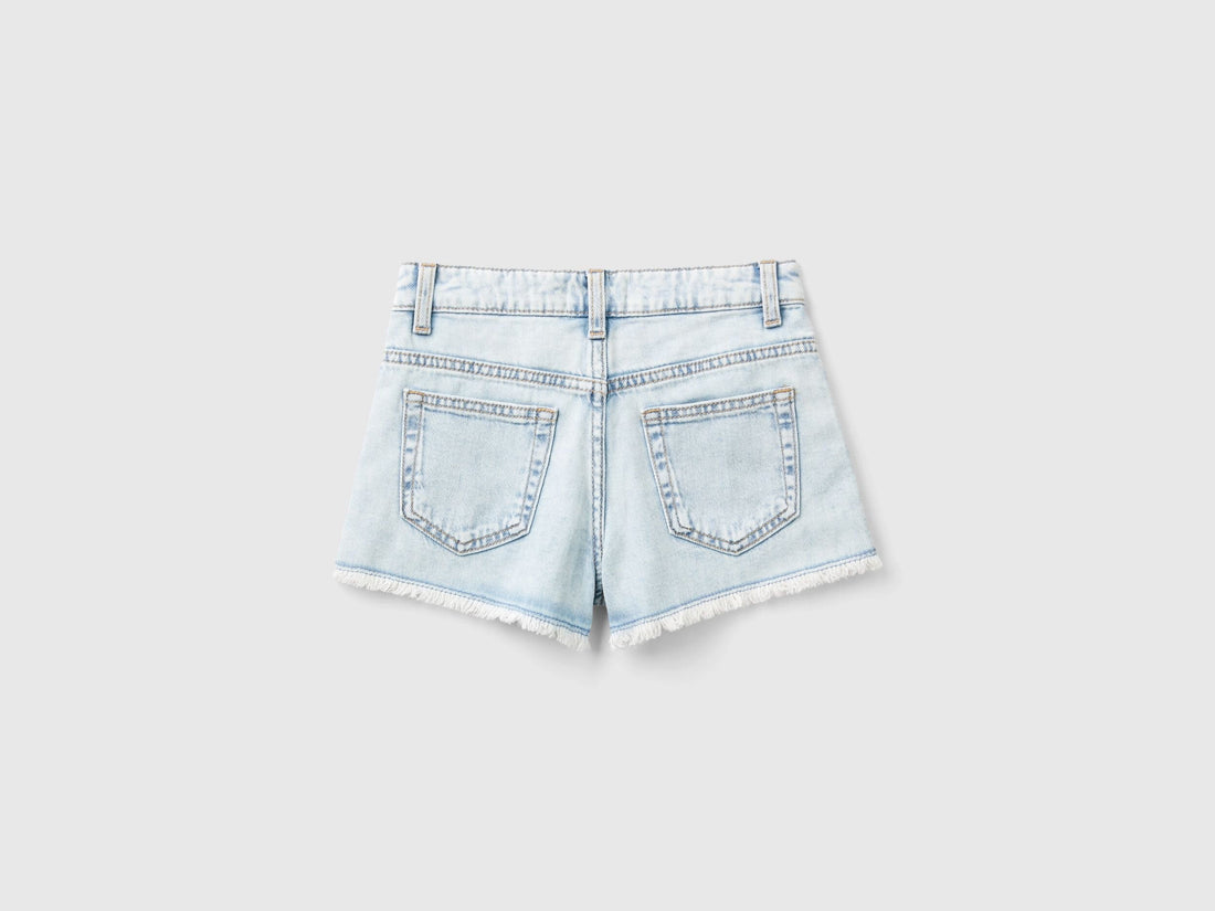 Back view of light wash denim shorts for girls with butterfly embroidery.