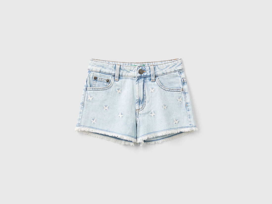 Front view of light wash denim shorts for girls with butterfly embroidery.