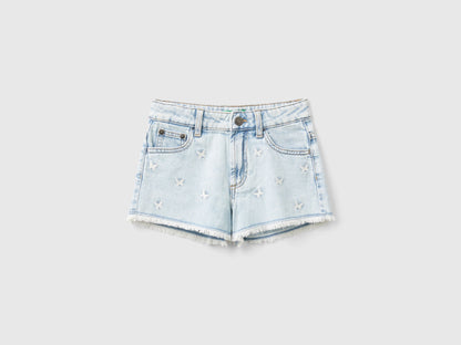 Front view of light wash denim shorts for girls with butterfly embroidery.