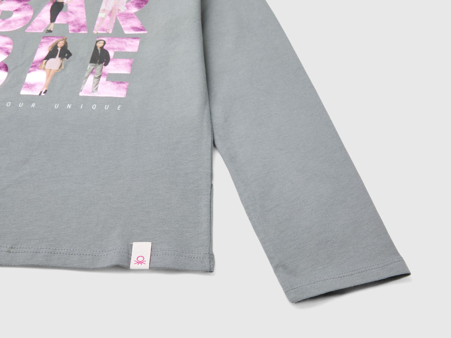 Close-up of gray Barbie t-shirt showing graphic print and sleeve with tag.
