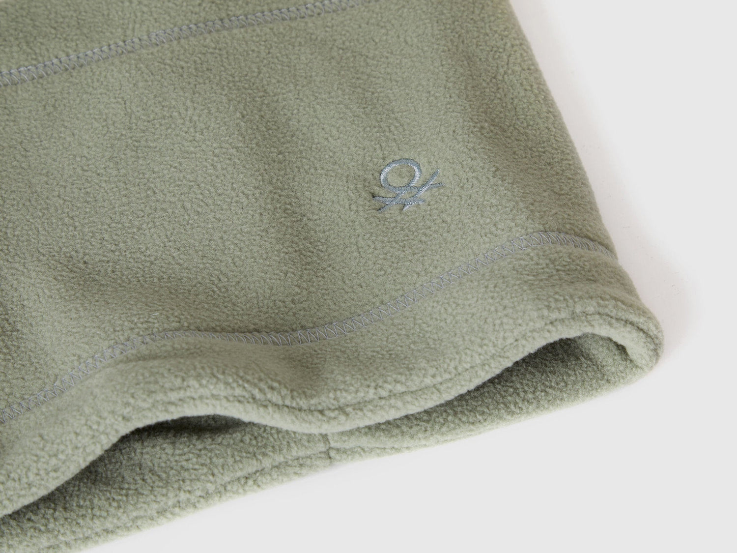 Close-up of green fleece neck warmer with Benetton logo.