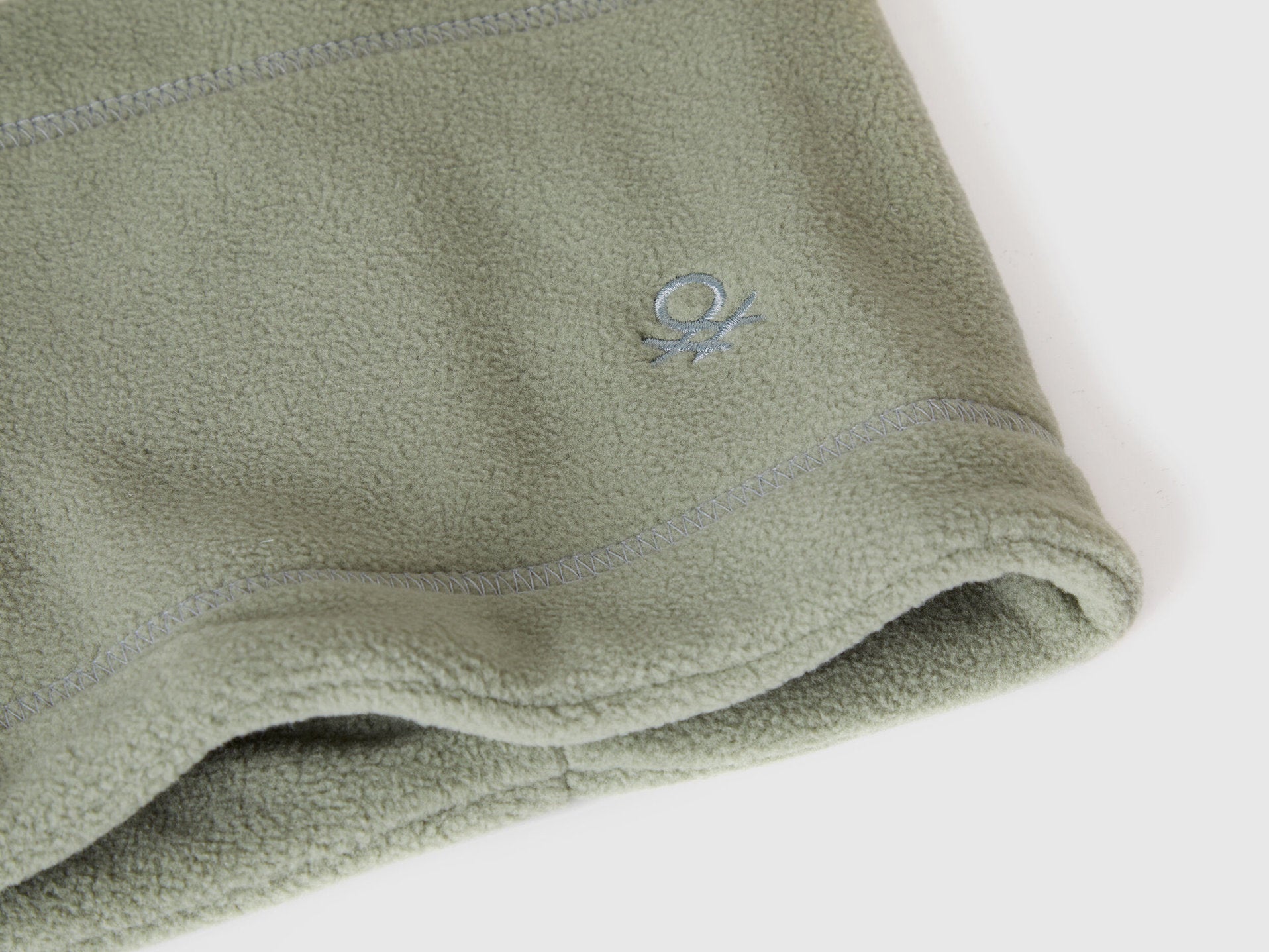 Close-up of green fleece neck warmer with Benetton logo.