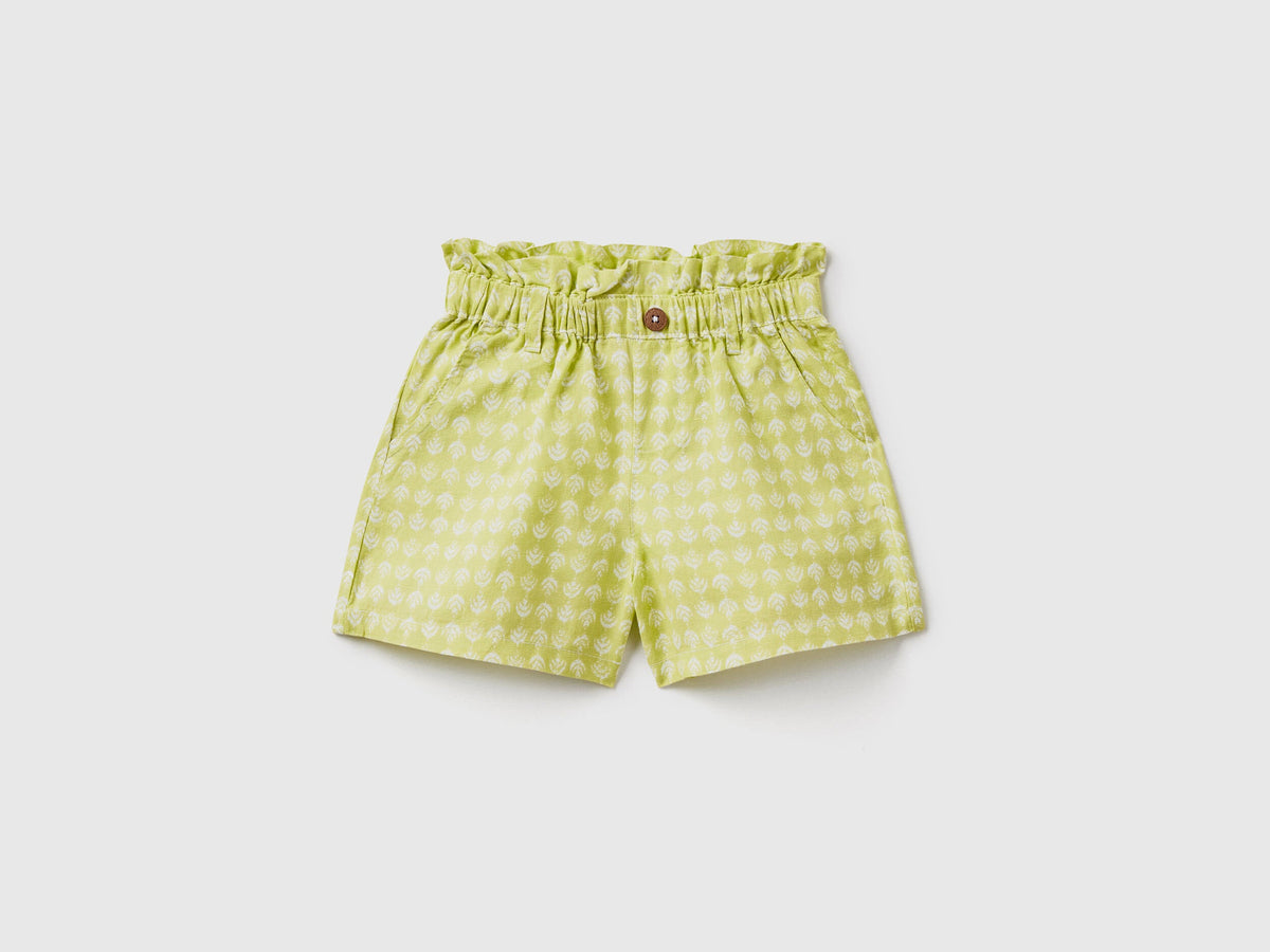 A flat lay, front view of a pair of green linen-blend shorts with a paperbag waist and a matching tie belt, a fashionable choice for the climate in Kuwait.