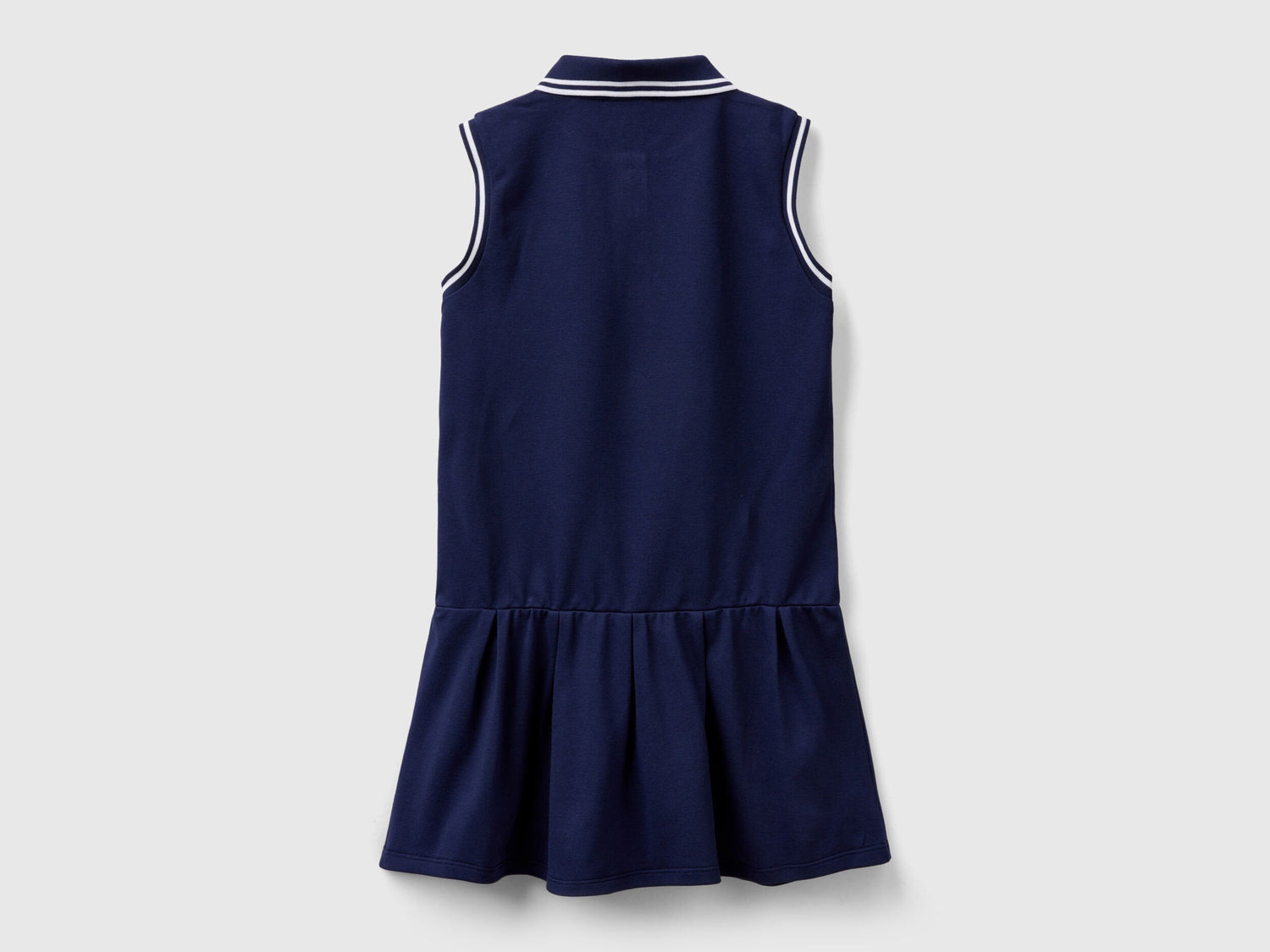 Back view of a navy blue polo dress for kids, with white striped trim on the collar and a ruffled skirt.