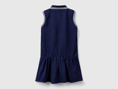 Back view of a navy blue polo dress for kids, with white striped trim on the collar and a ruffled skirt.