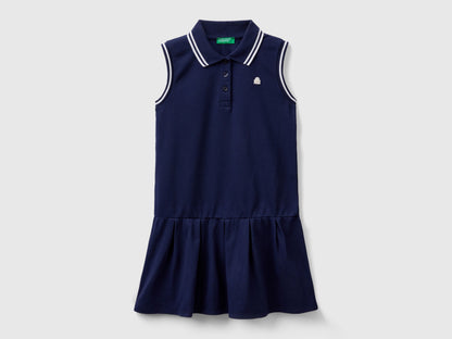 Front view of a navy blue polo dress for kids, featuring a white striped collar and ruffled skirt.