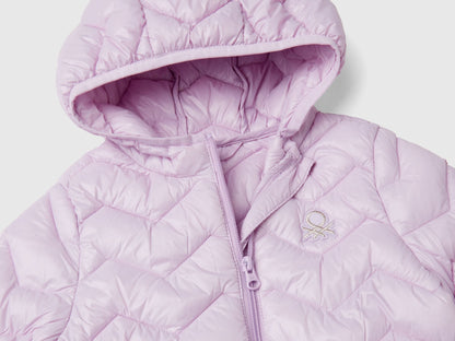 Close-up of a light pink padded jacket for a girl, showing hood, zipper, and logo.