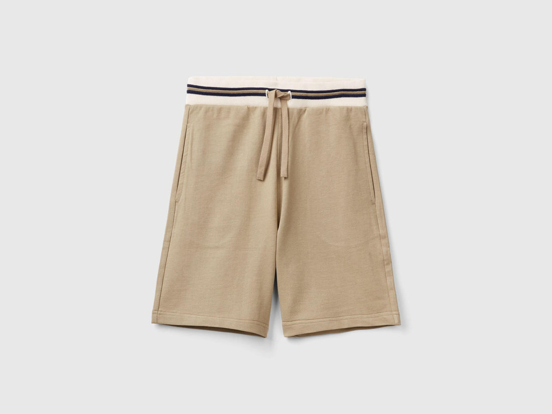 Front view of lightweight beige sweat shorts with a striped waistband.