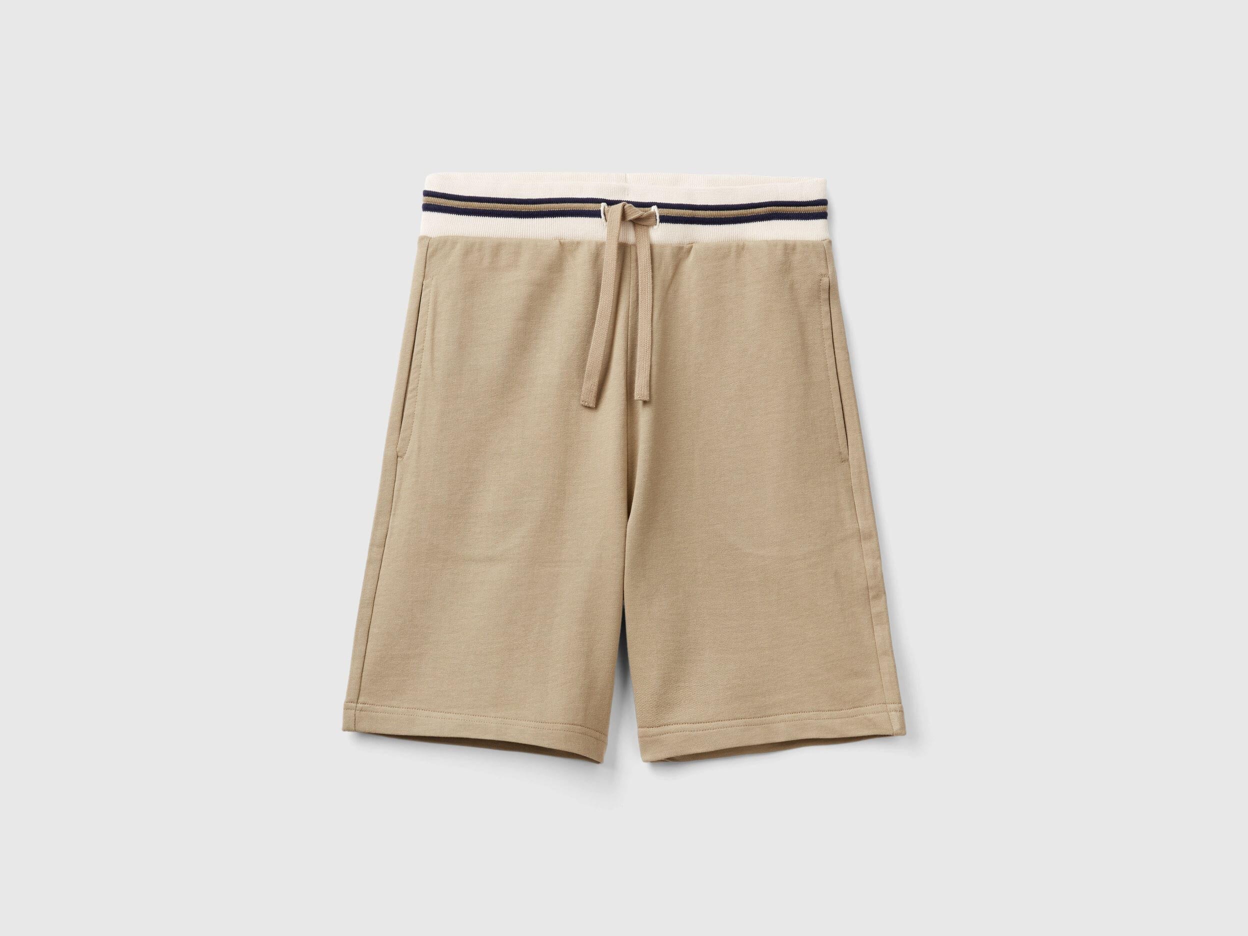 Front view of lightweight beige sweat shorts with a striped waistband.