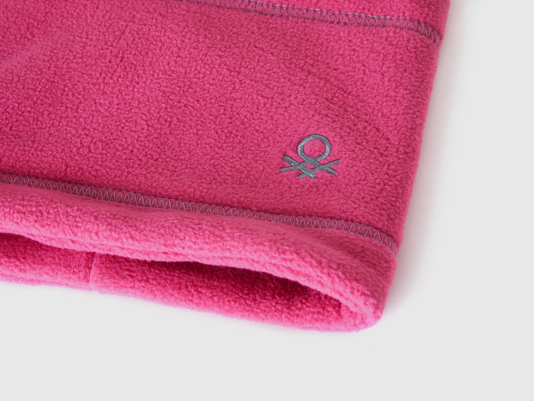 Close-up of magenta fleece neck warmer with Benetton logo.