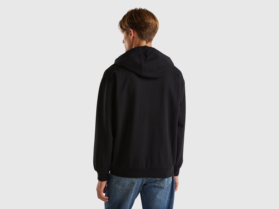 Back view of a man wearing a plain black hoodie.