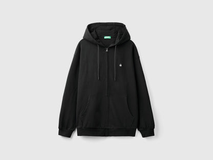 Side view of a man wearing a plain black pullover hoodie.