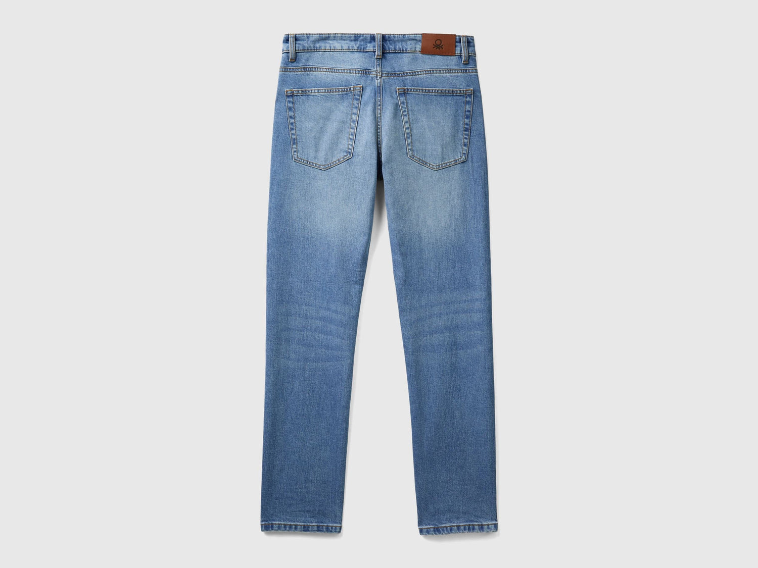 Close-up of the back pocket and leather patch on blue five-pocket jeans.