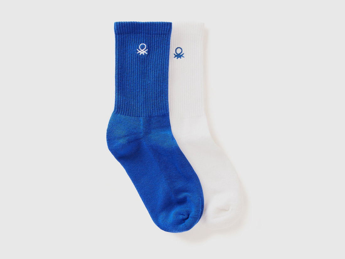A pair of athletic socks for men or boys, one royal blue and one white.