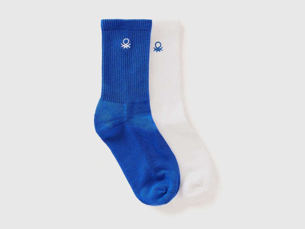 A pair of athletic socks for men or boys, one royal blue and one white.