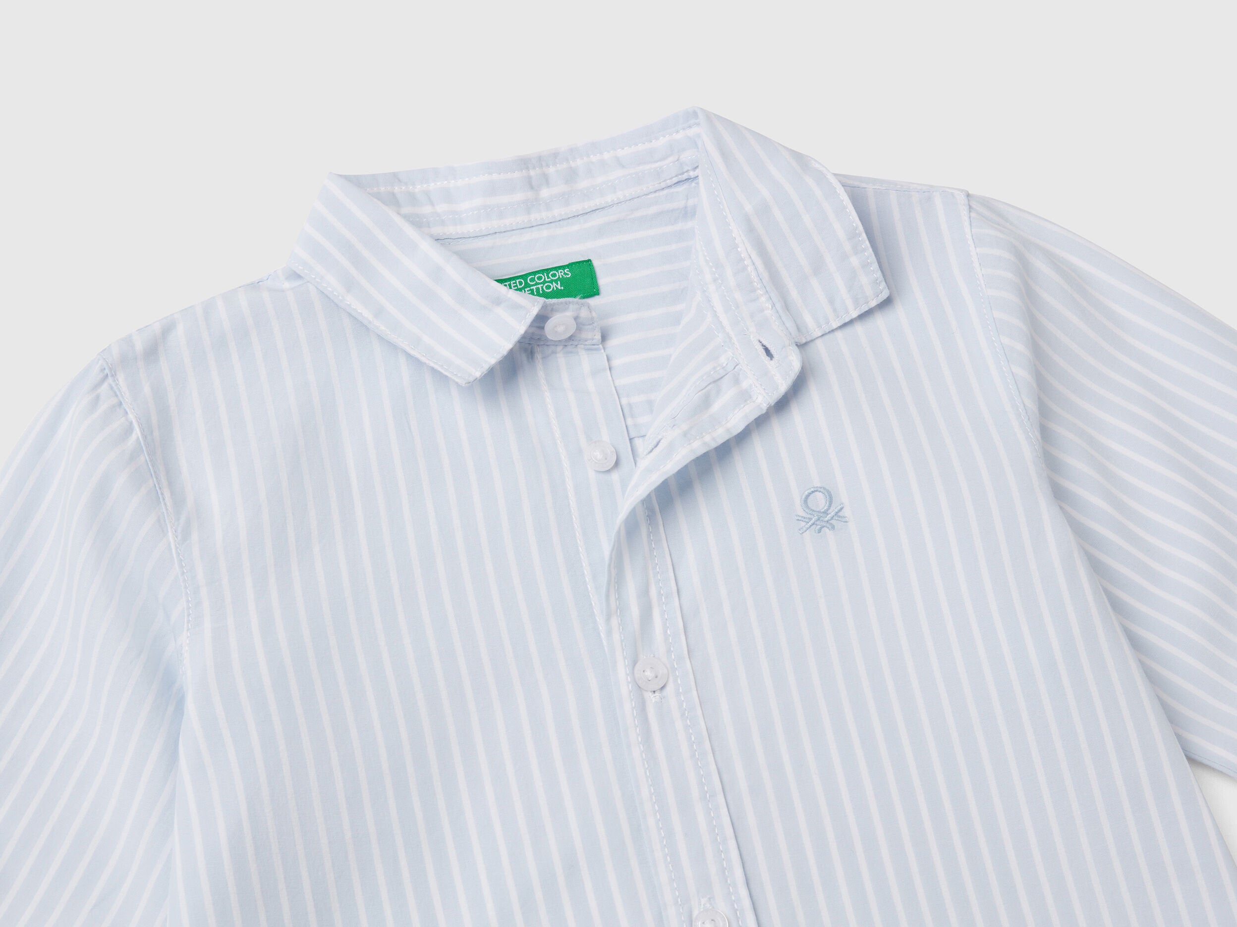 Close-up of a white and blue striped shirt for men or boys, showing collar and buttons.