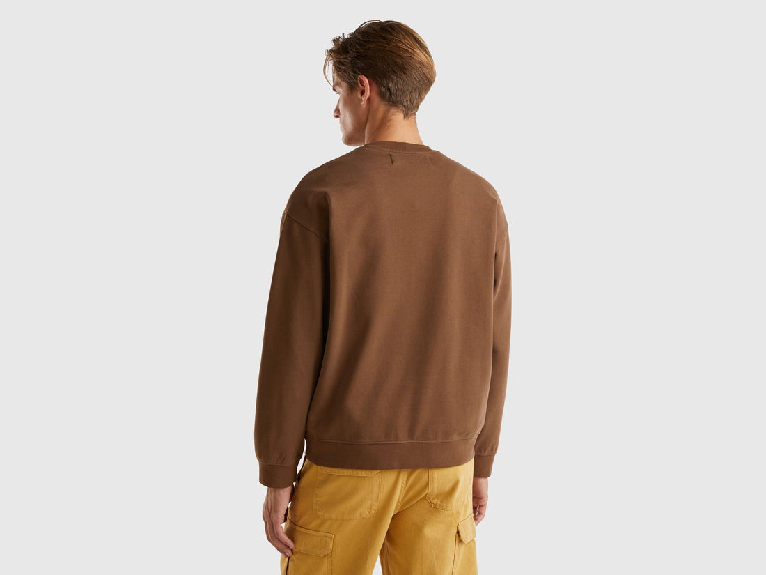 Back view of a man wearing a brown crew neck sweatshirt.