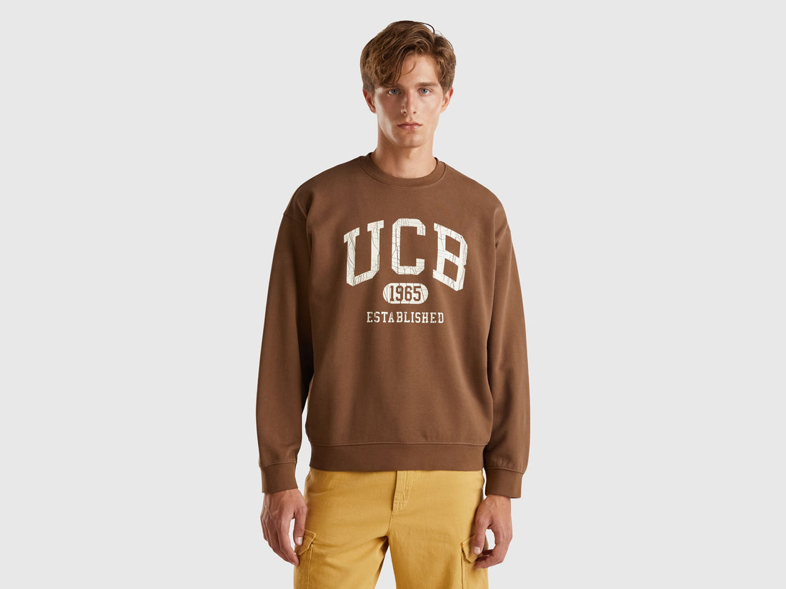 Front view of a man wearing a brown crew neck sweatshirt.