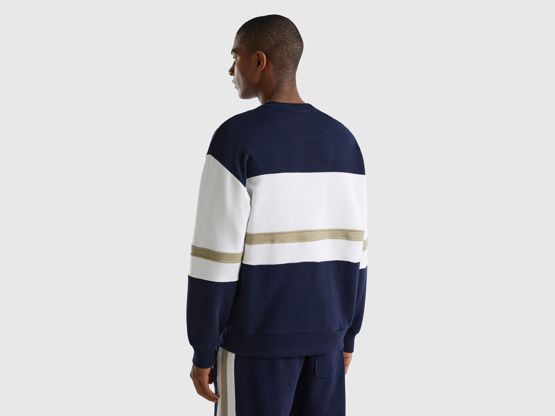 Back view of a man wearing a dark blue sweatshirt with a logo stripe.