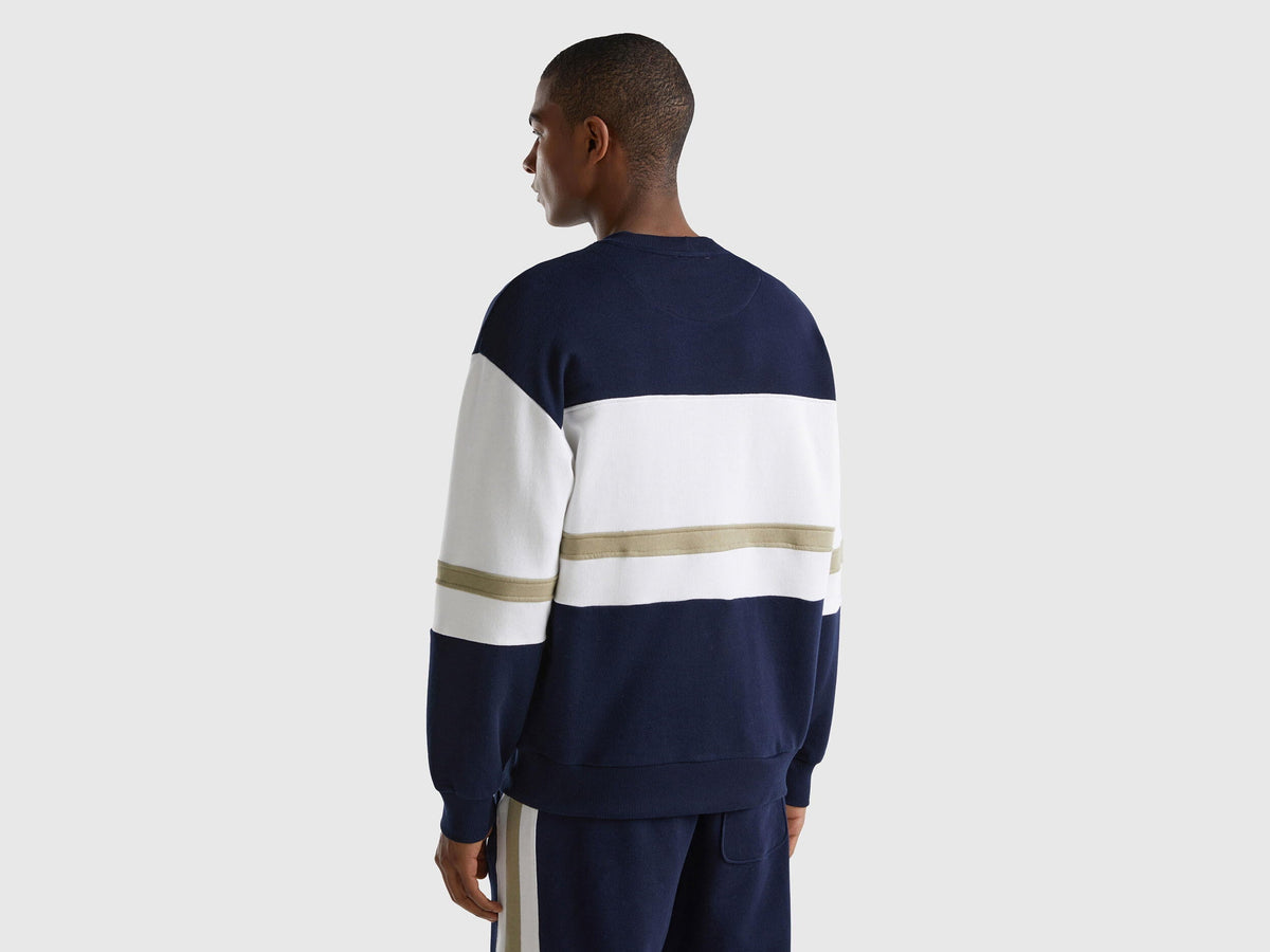 Back view of a man wearing a dark blue sweatshirt with a logo stripe.