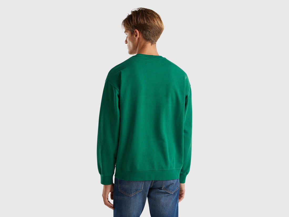Back view of a man wearing a plain green crew neck sweatshirt.