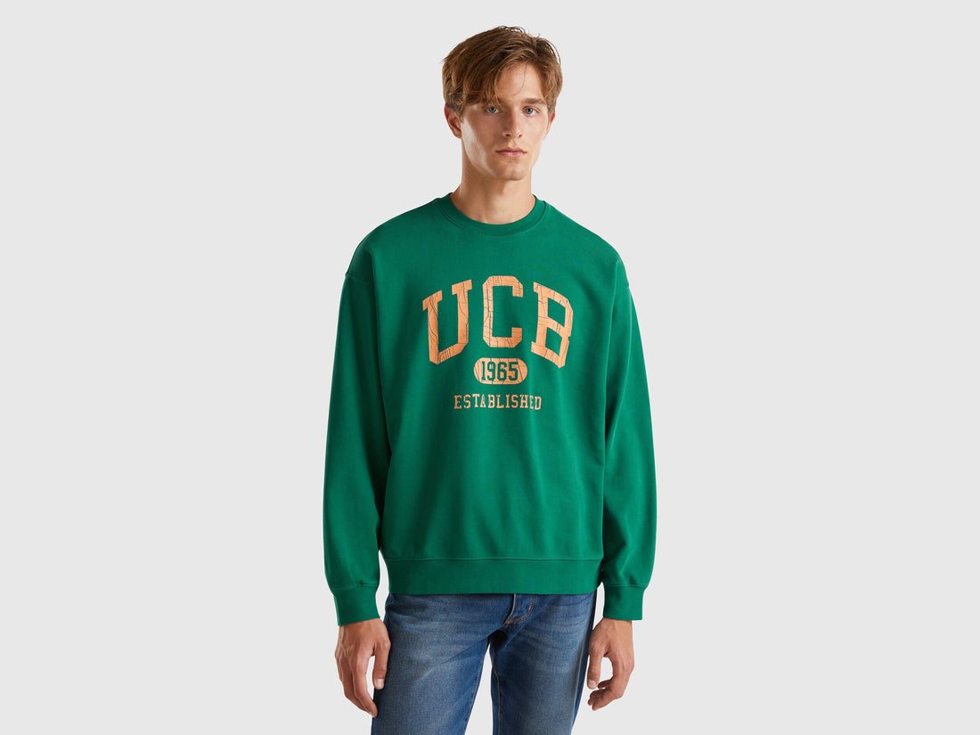 Front view of a man wearing a plain green crew neck sweatshirt.