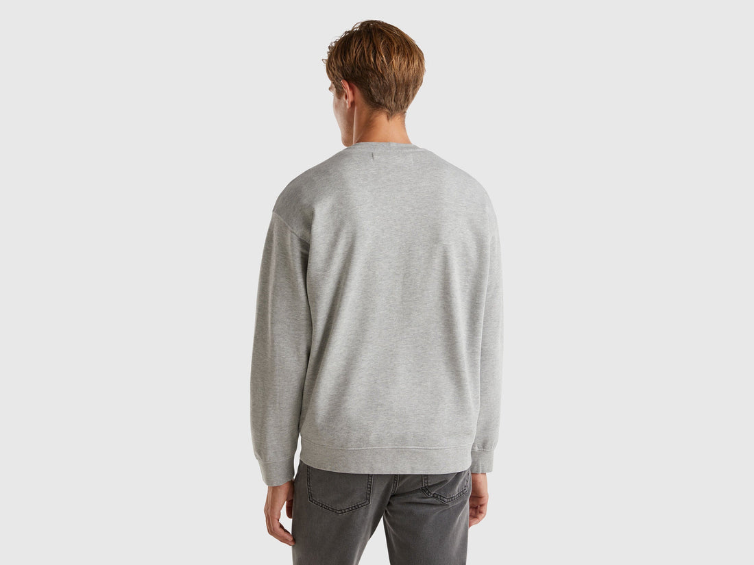 Back view of a man wearing a light grey crew neck sweatshirt.