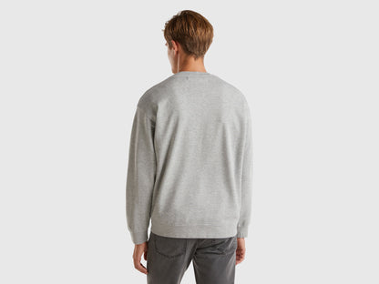 Back view of a man wearing a light grey crew neck sweatshirt.