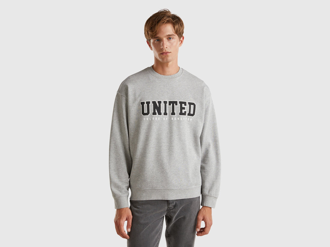 Front view of a man wearing a light grey crew neck sweatshirt.