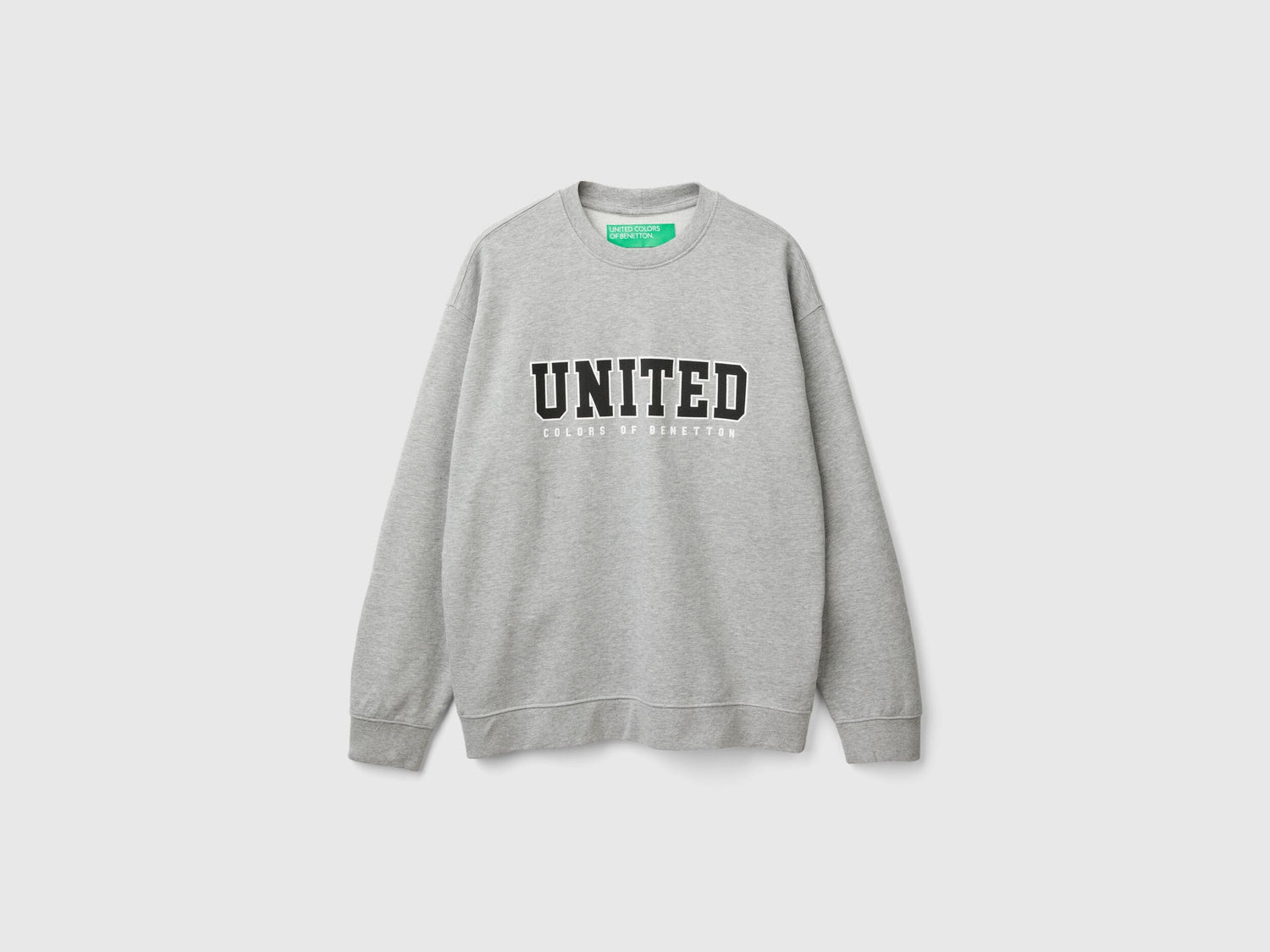 Side view of a man wearing a light grey crew neck sweatshirt.
