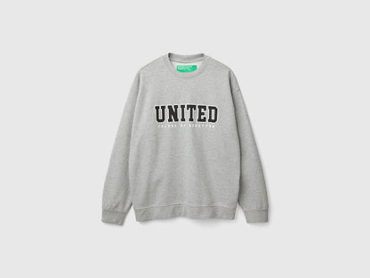 Side view of a man wearing a light grey crew neck sweatshirt.