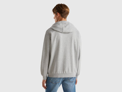 Back view of a man wearing a plain grey zip-up hoodie.