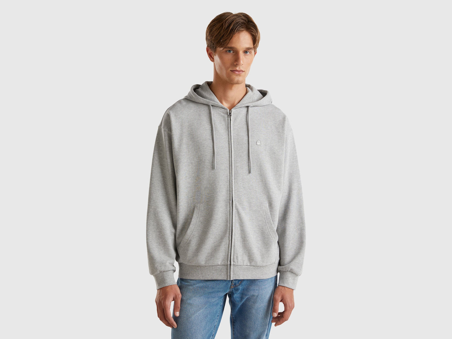 Front view of a man wearing a plain grey zip-up hoodie.