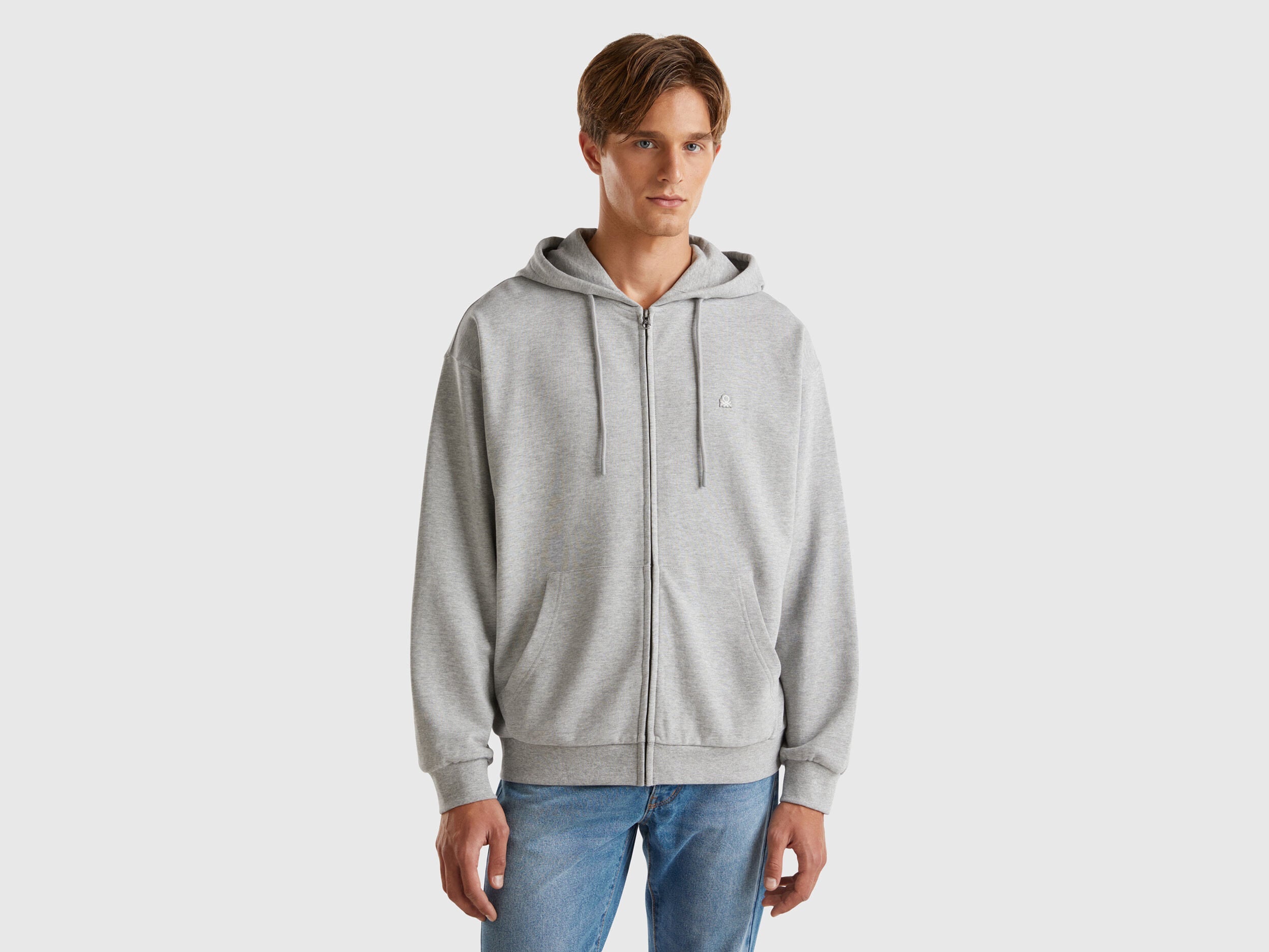 Front view of a man wearing a plain grey zip-up hoodie.
