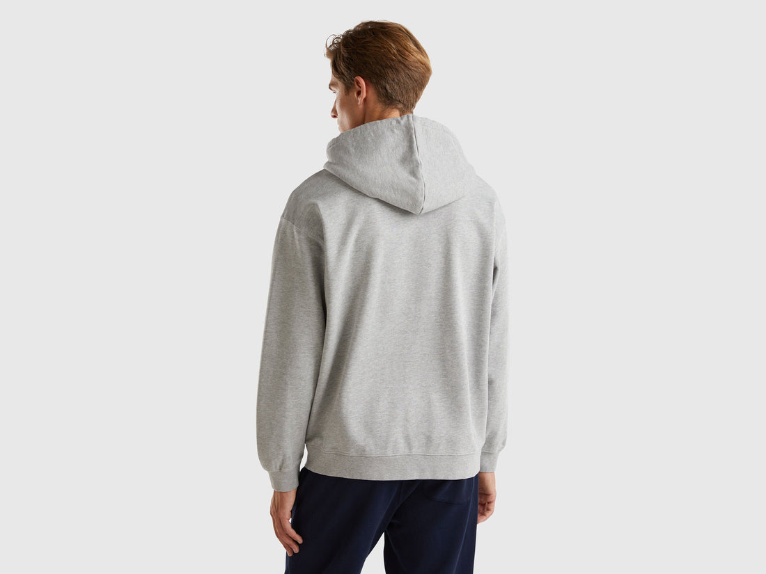 Back view of a man wearing a navy blue 100% cotton hoodie.