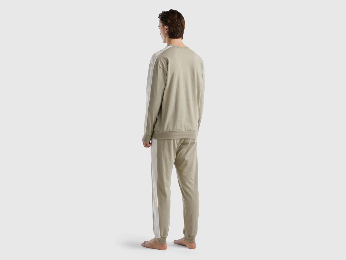 Back view of a man wearing beige pyjamas with side stripes in Kuwait.