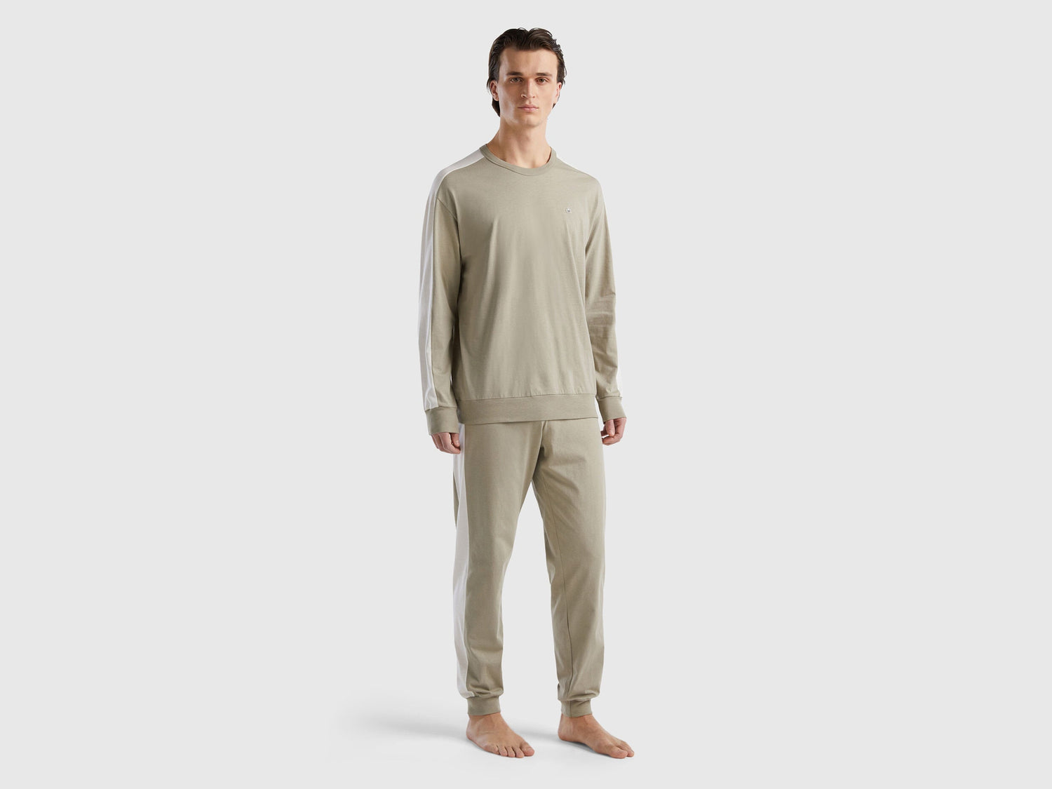 Front view of a man wearing beige pyjamas with side stripes in Kuwait.