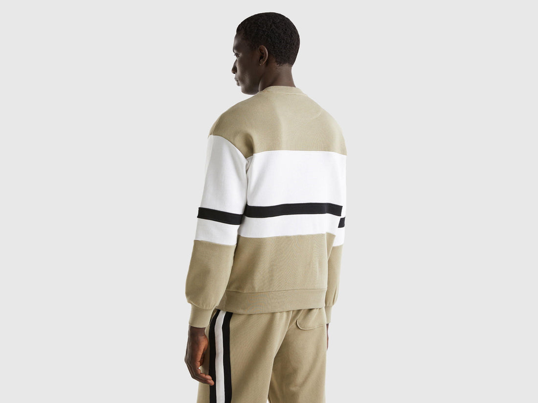 Back view of a man wearing a sage green sweatshirt with a black and white stripe.