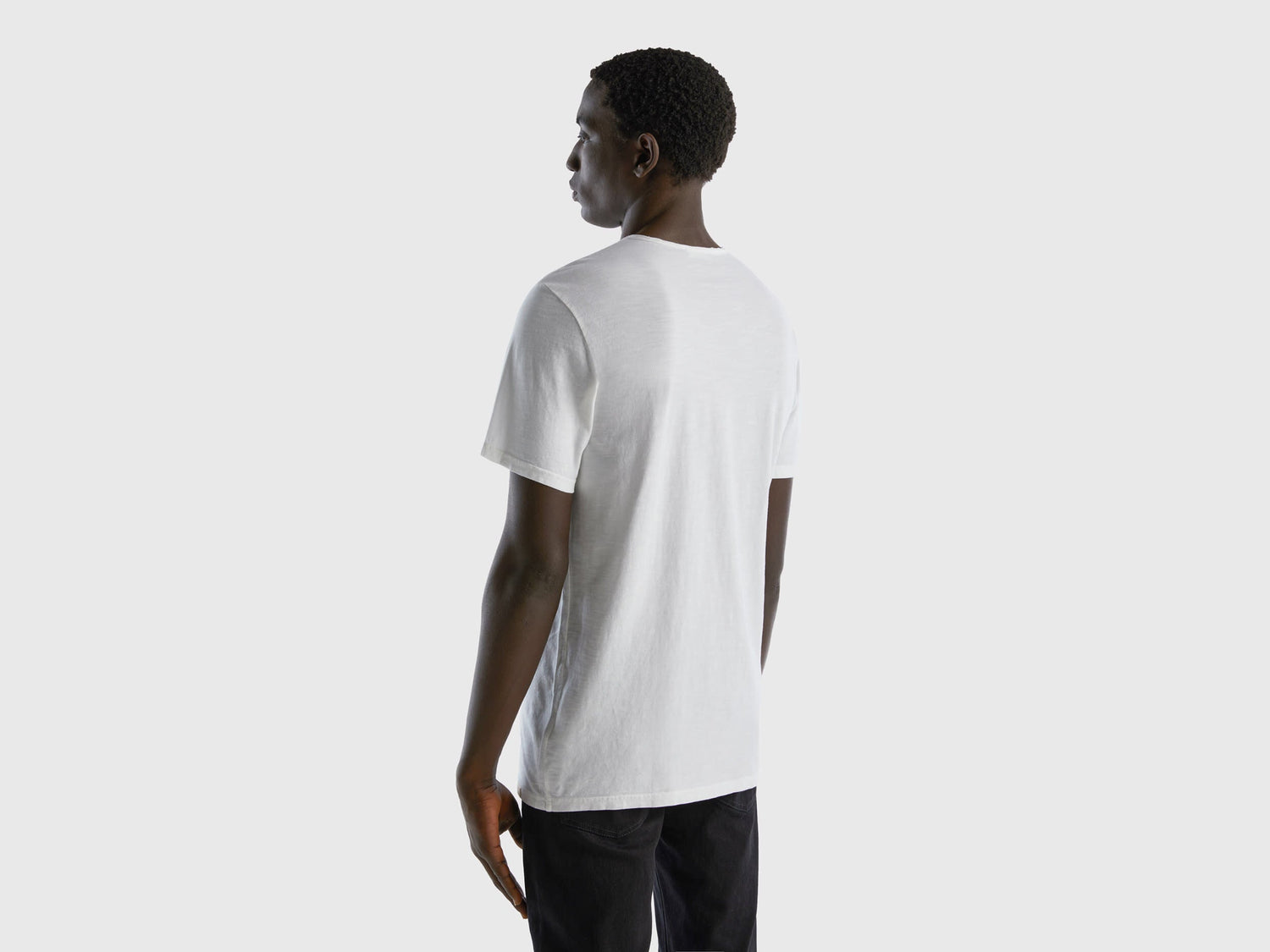 Back view of a man wearing a white V-neck t-shirt.