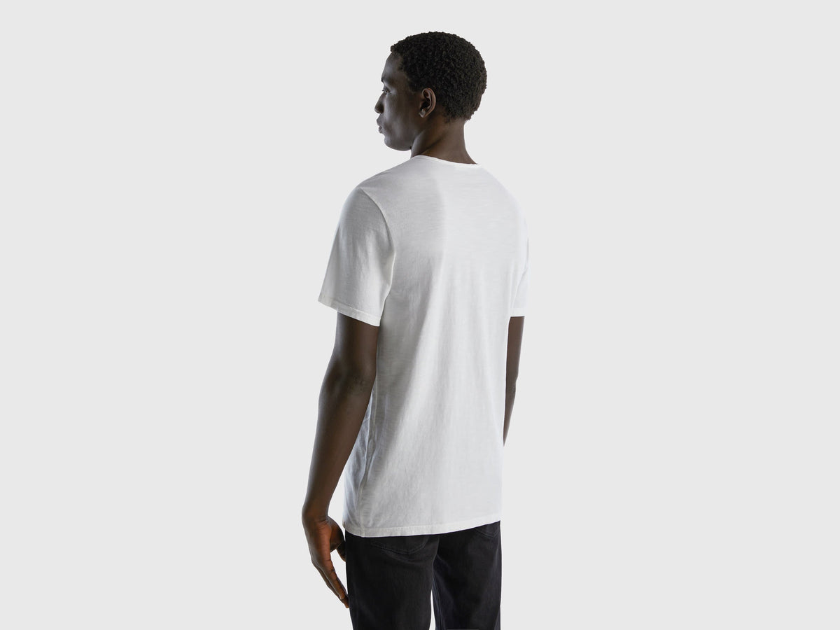 Back view of a man wearing a white V-neck t-shirt.