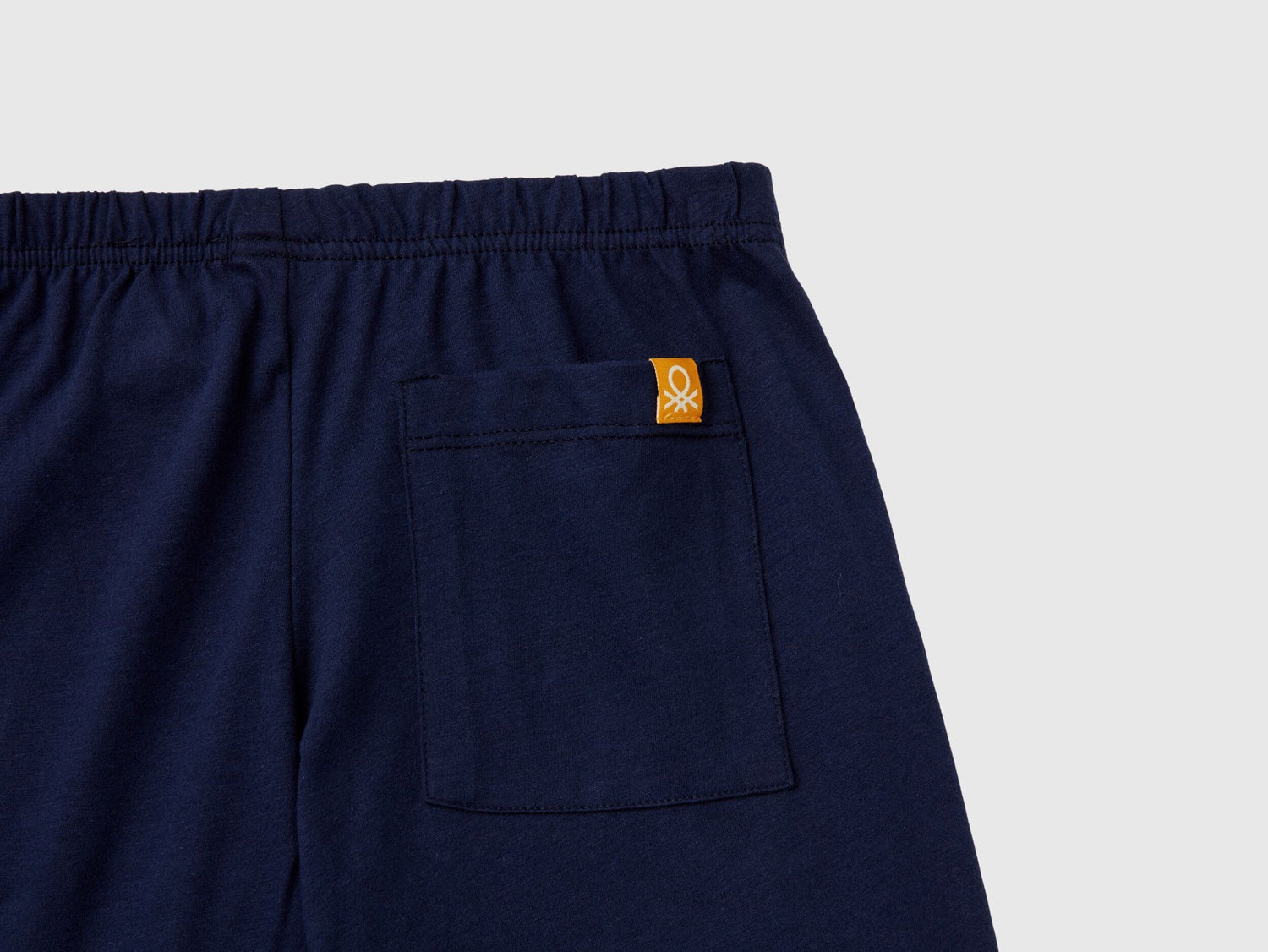 Close-up of the navy blue pyjama bottoms, highlighting the fabric texture and a small Benetton logo on the back pocket, essential details for quality pyjamas Kuwait and sleepwear Kuwait.