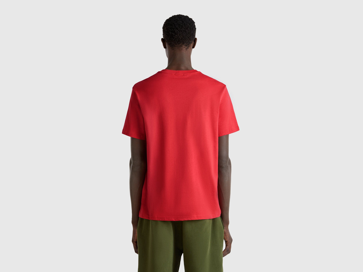  Close-up of the ribbed crew neck and shoulder seam of a red T-shirt for men in Kuwait, highlighting the quality and stitching.