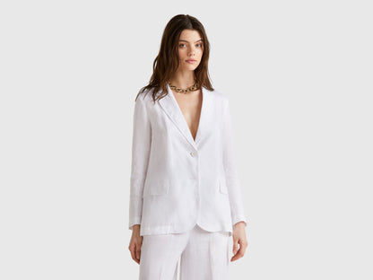 Female model wearing a white pure linen Benetton blazer with matching wide-leg pants, in a relaxed, elegant pose.
