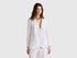 Female model wearing a white pure linen Benetton blazer with matching wide-leg pants, in a relaxed, elegant pose.