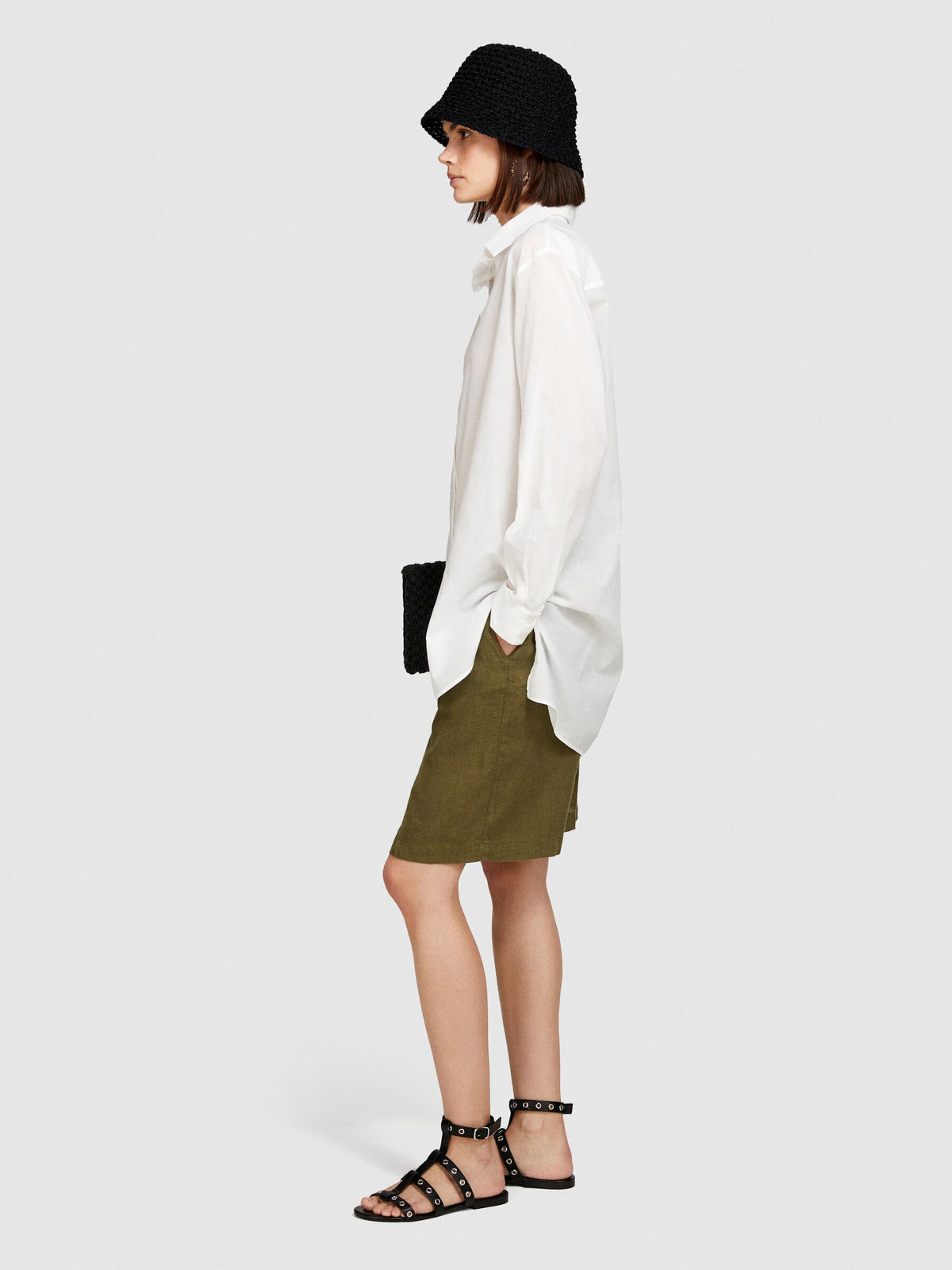 Back view of a model wearing an oversized white shirt and khaki shorts.