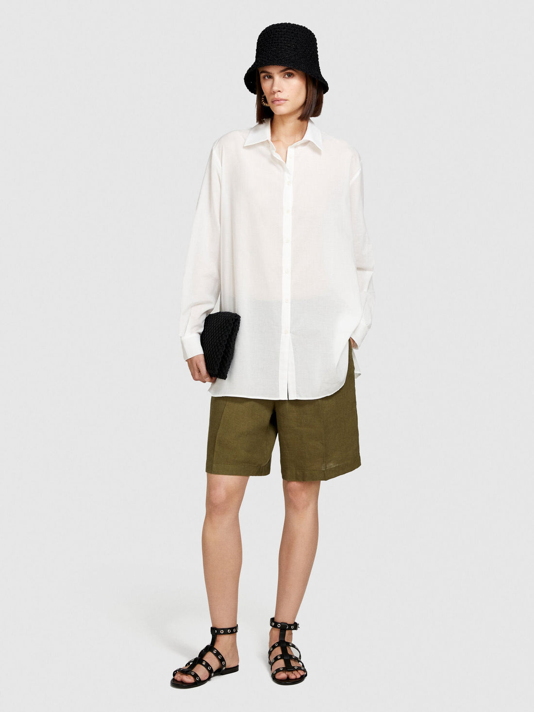 Side view of a model in an oversized white shirt and khaki shorts.